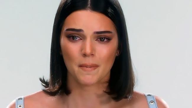 Close-up image of Kendall Jenner, with a plain background. She is biting her lip holding back tears during a ‘Keeping Up With the Kardashians’ interview. 