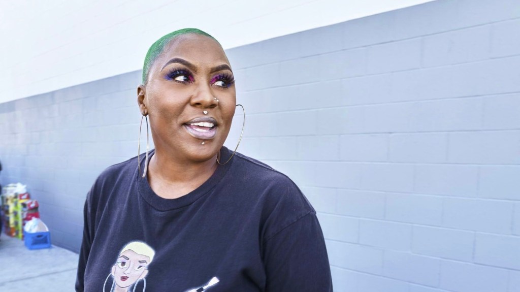 Shirley Raines green hair smiling while looking to the side of the screen. 